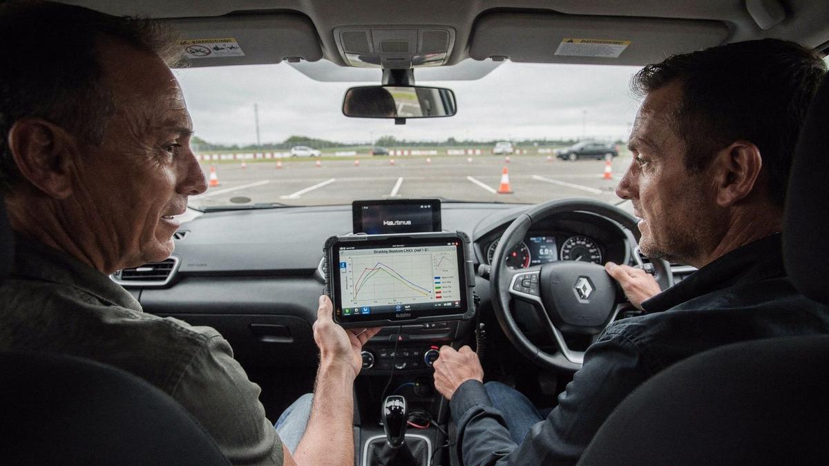 Instructor and driver reviewing braking telemetry on a tablet inside the training car